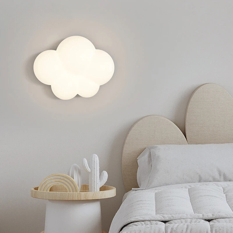 Cloud-shaped wall lamp in a bedroom setting with a bed and nightstand.