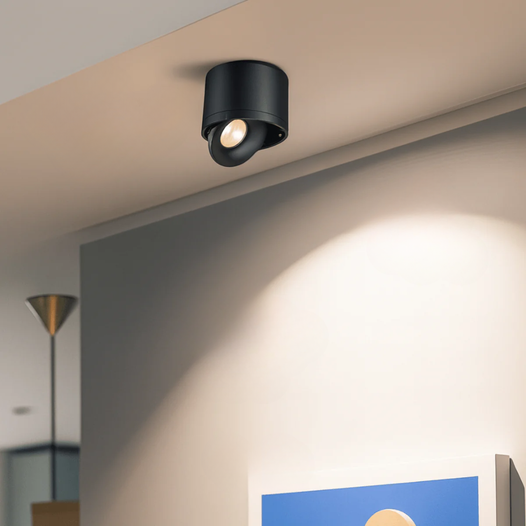 Black ceiling light fixture on a beige ceiling with a soft glow on the wall.