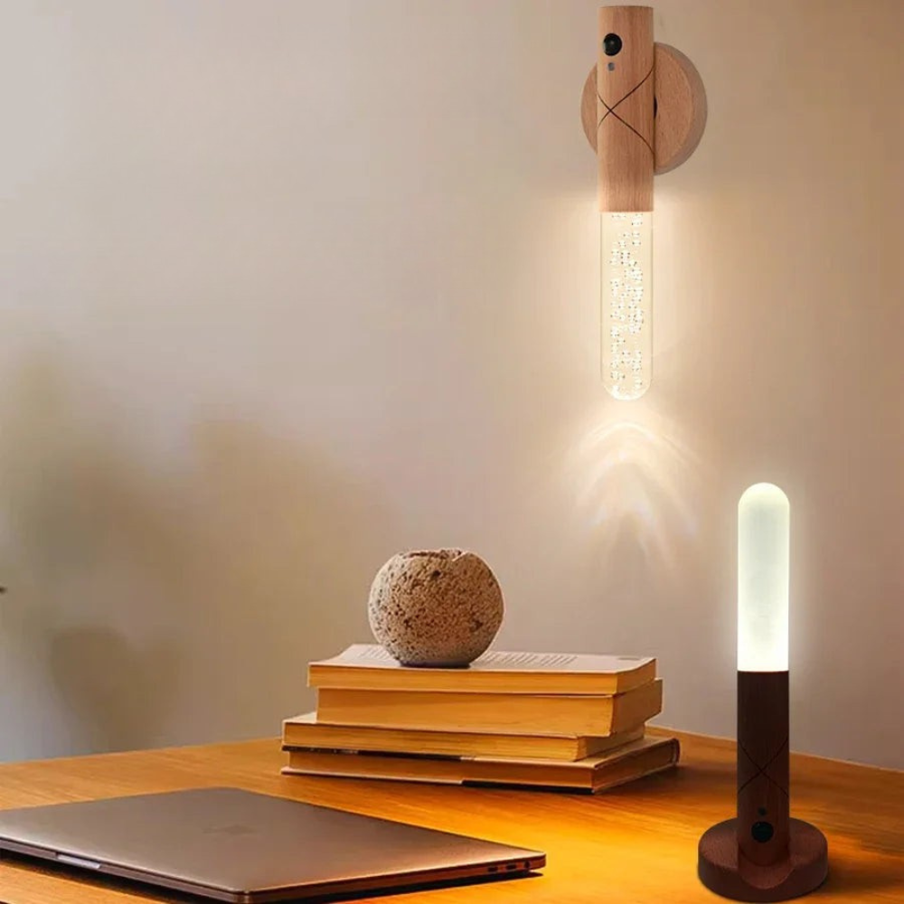 Wooden wall lamp and table lamp on a wooden surface with books and a rock.