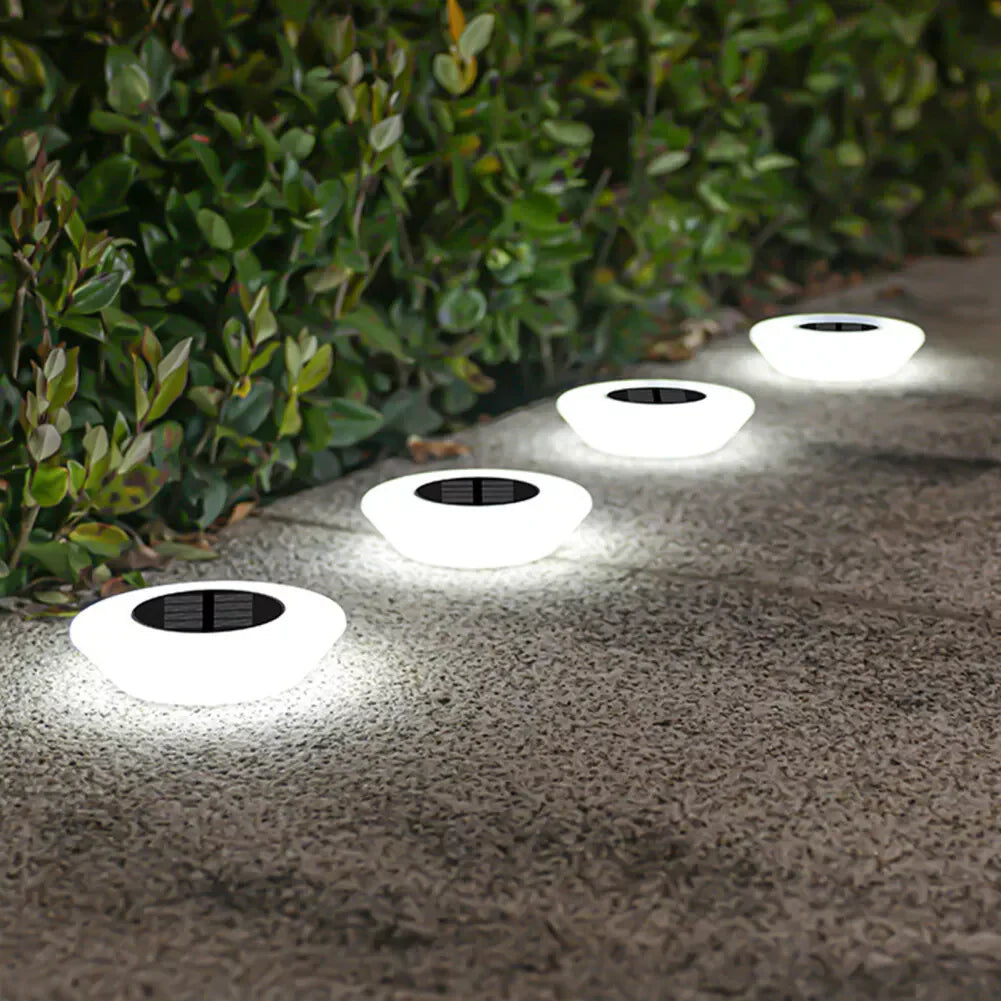 Solar-powered outdoor lights on a concrete surface with greenery in the background
