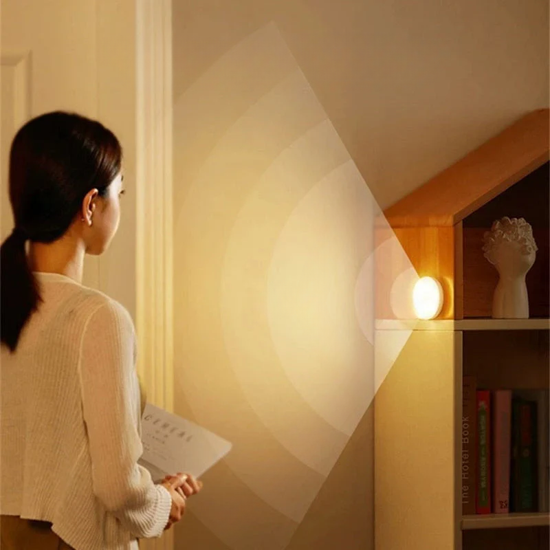 Woman standing in a room with a light fixture casting a warm glow.