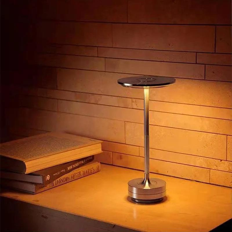 Small round table with a lamp on a wooden surface against a wooden wall.