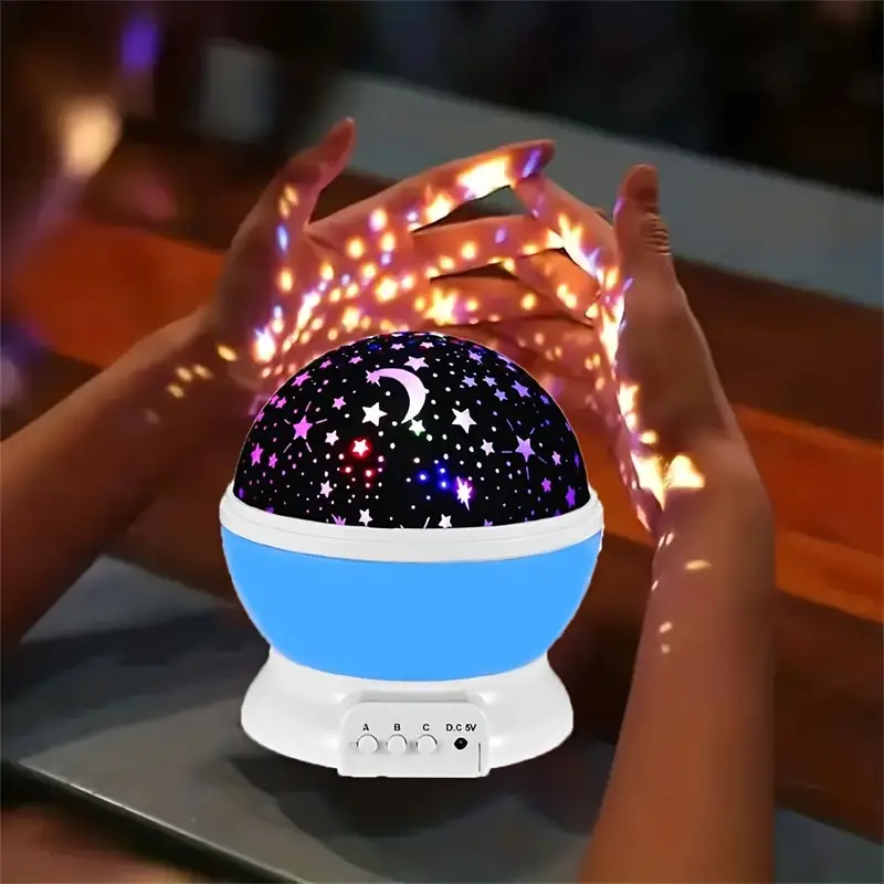Starry night light projector with colorful star and moon design, held by hands.