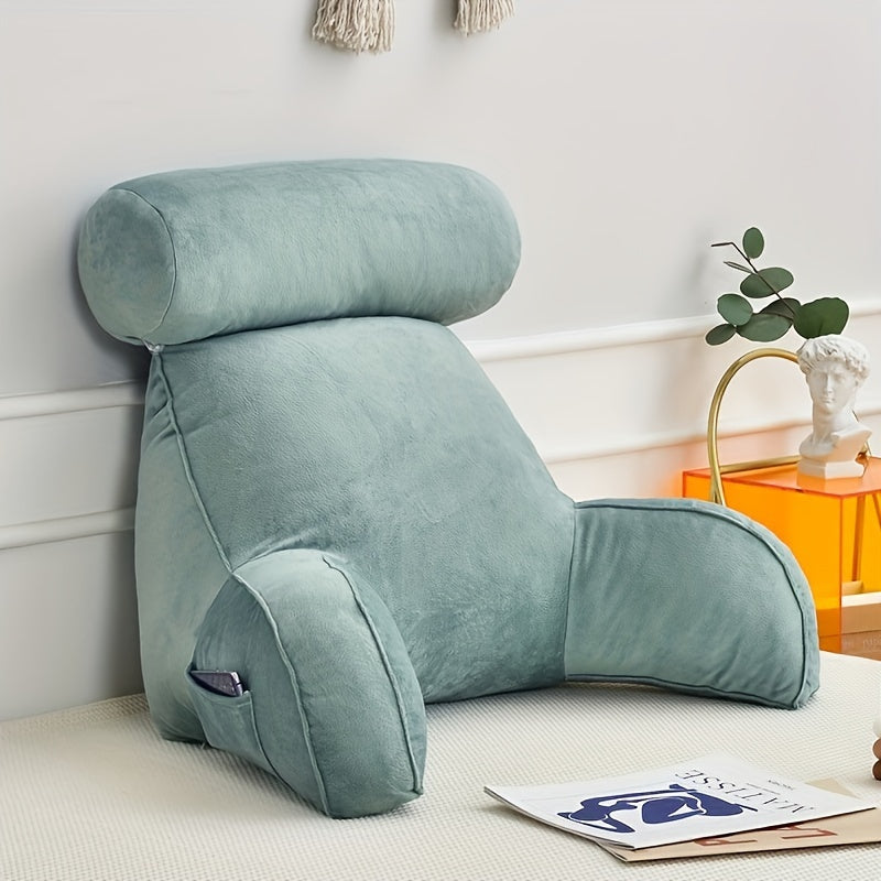 Green backrest pillow on a bed with a white wall and orange side table in the background