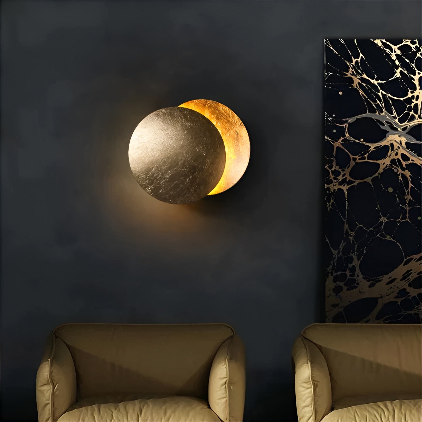 Wall-mounted moon lamp with two beige armchairs and a marble-patterned wall art piece.