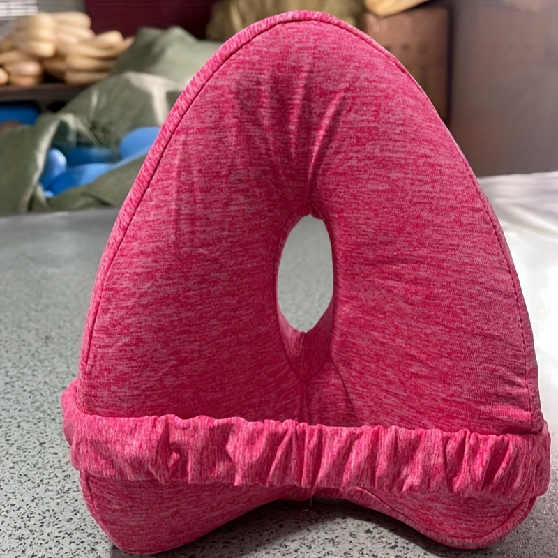 Pink U-shaped pillow on a surface with a blurred background