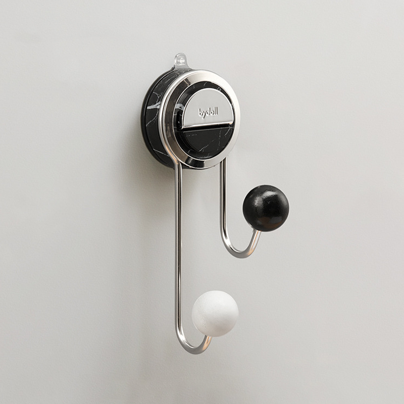 Wall-mounted hook with black and white hooks on a light gray background