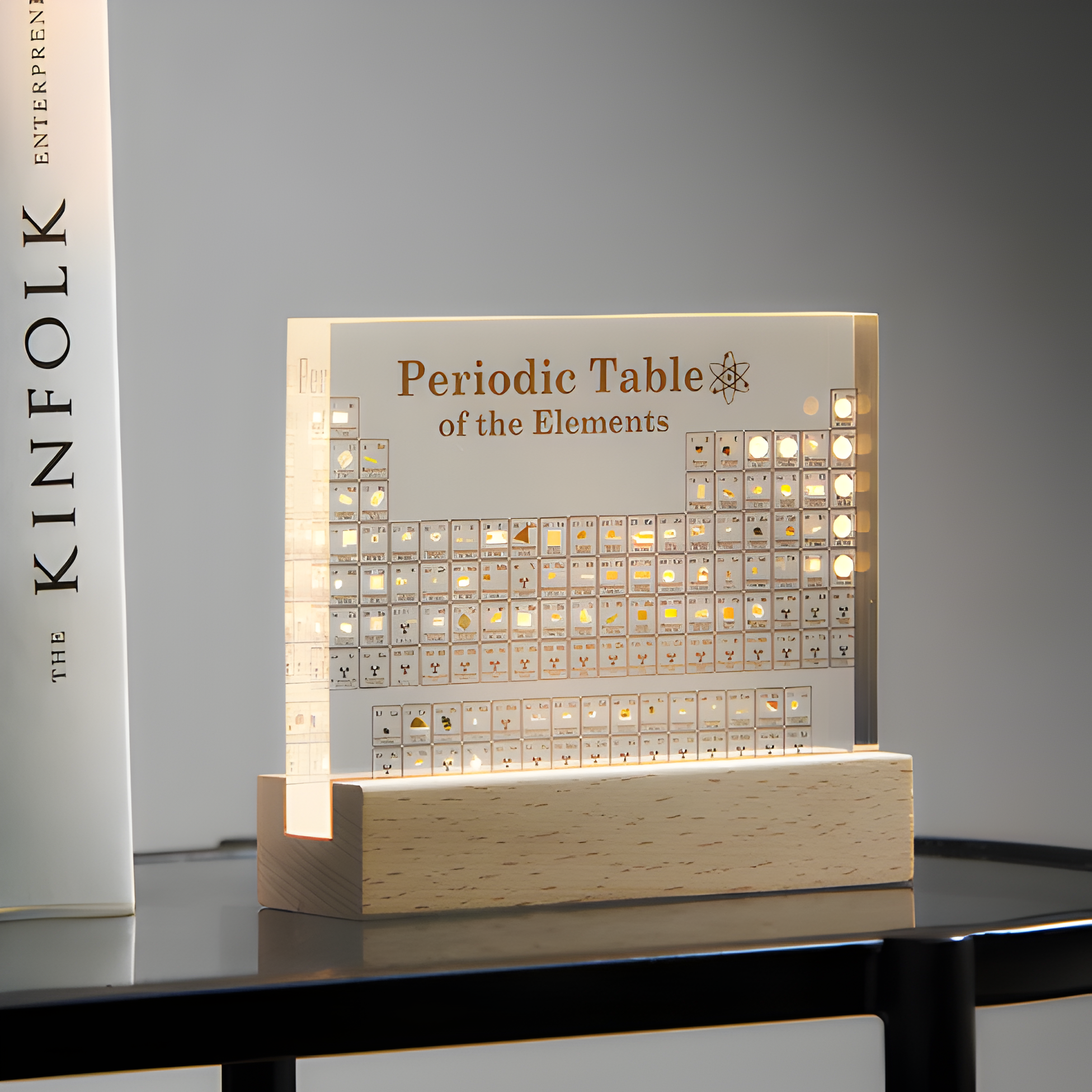 Light-up periodic table of elements on a wooden base with a gray background