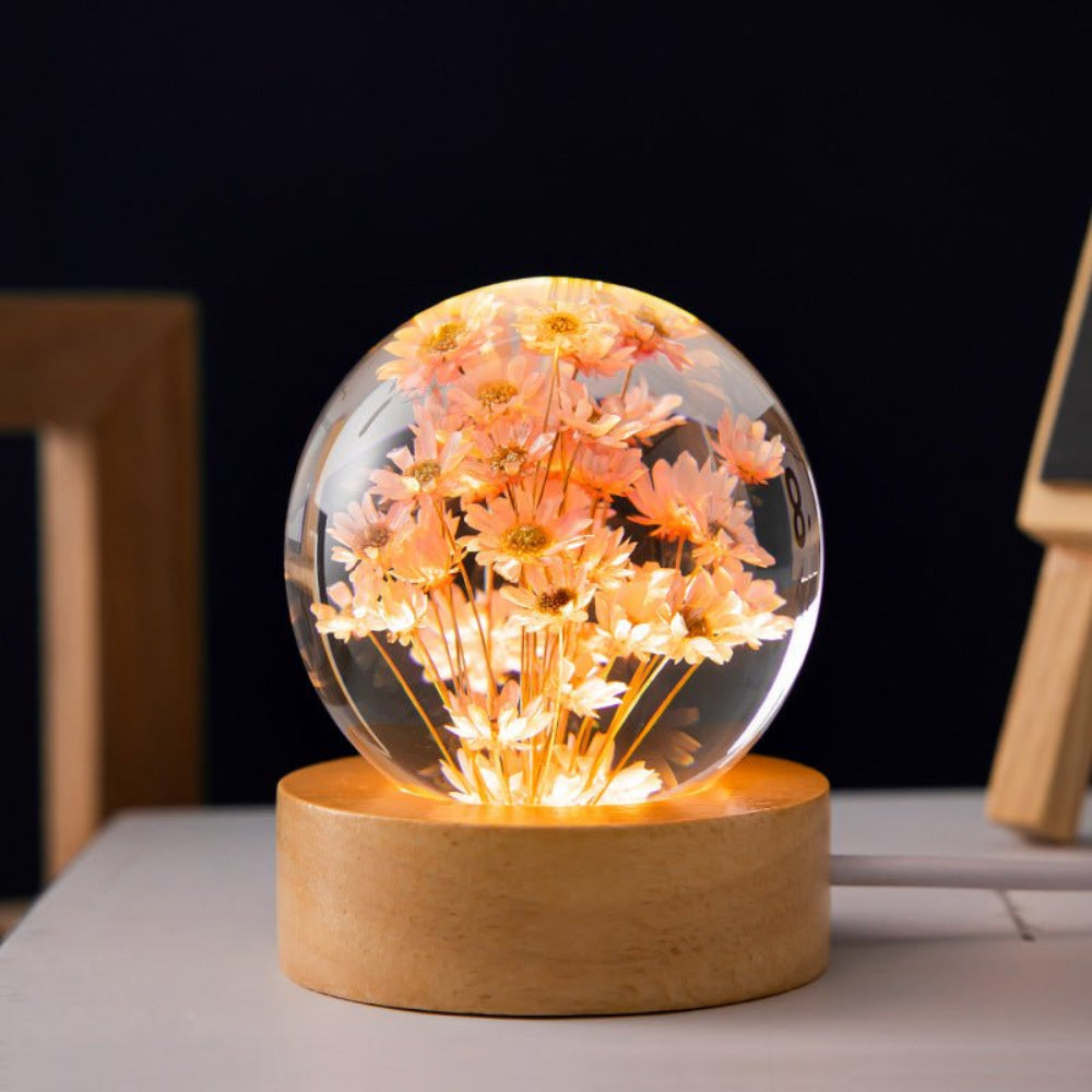 Decorative lamp with a glass sphere containing flowers on a wooden base