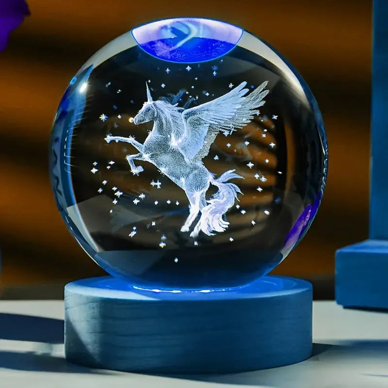 Glass orb with a unicorn design on a blue stand against a blurred background