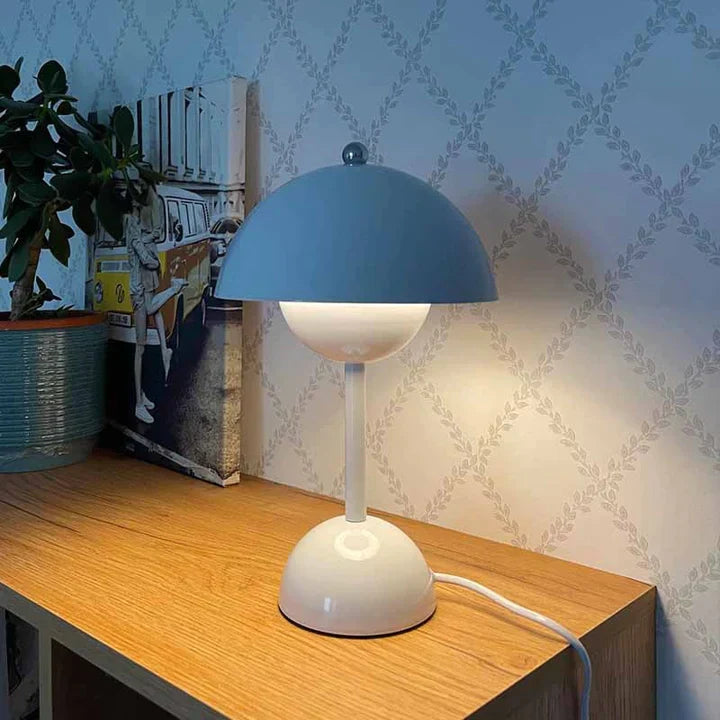 Blue and white table lamp on a wooden surface with decorative wallpaper in the background