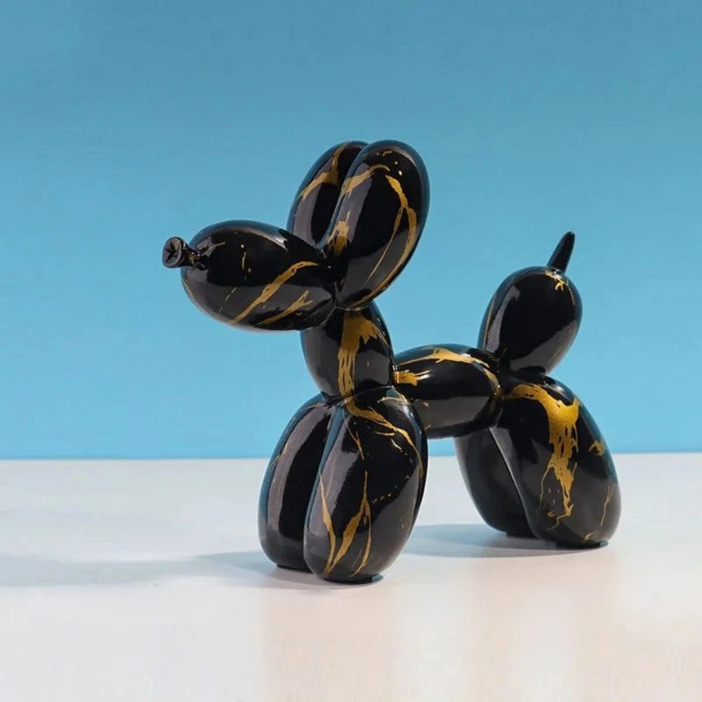 Black and gold balloon dog sculpture on a white surface with a blue background