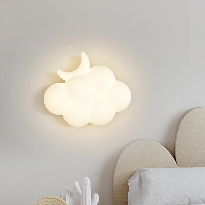 Cloud-shaped wall lamp on a light gray wall with a bed and decorative items in the foreground.