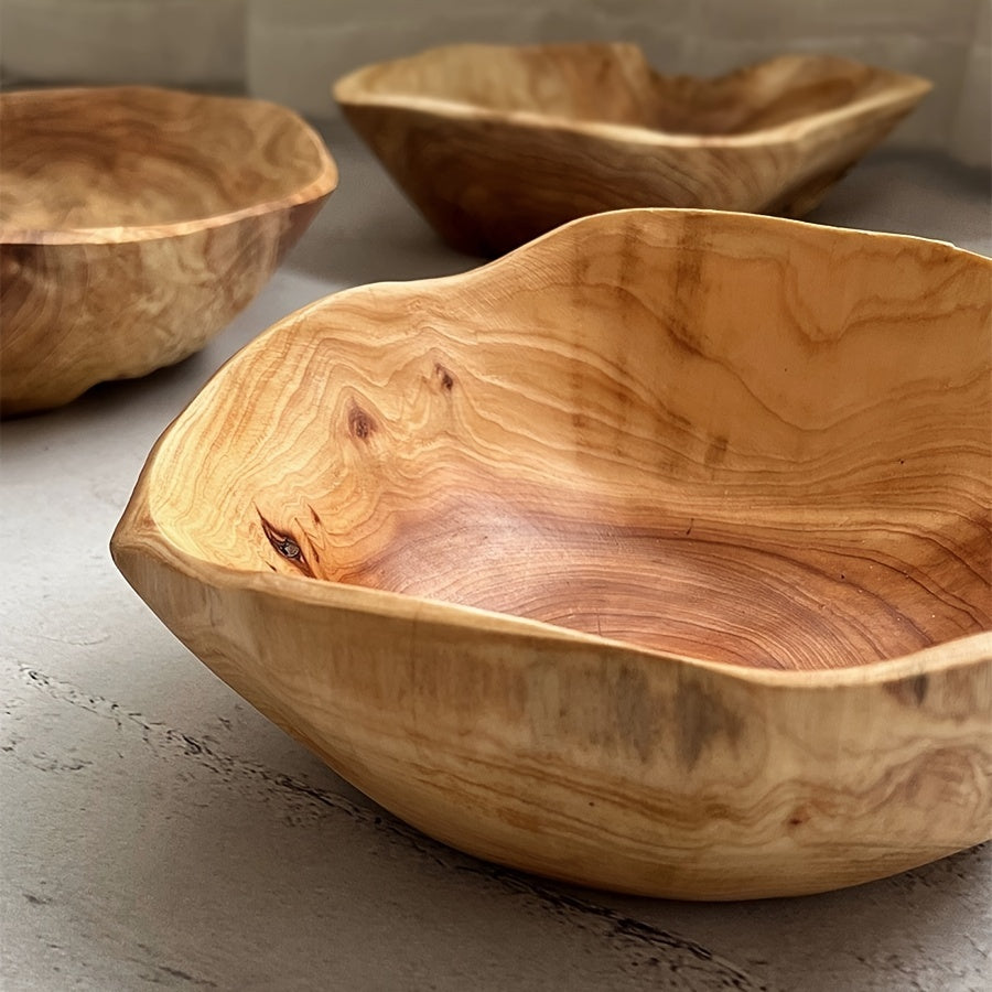Three wooden bowls with natural grain patterns on a light surface.