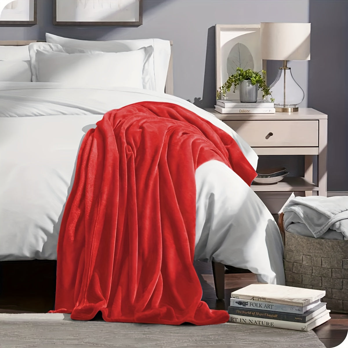 Red blanket draped over a bed in a bedroom setting with a nightstand and lamp.