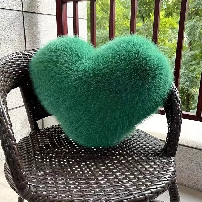 Green heart-shaped fluffy pillow on a wicker chair outdoors.
