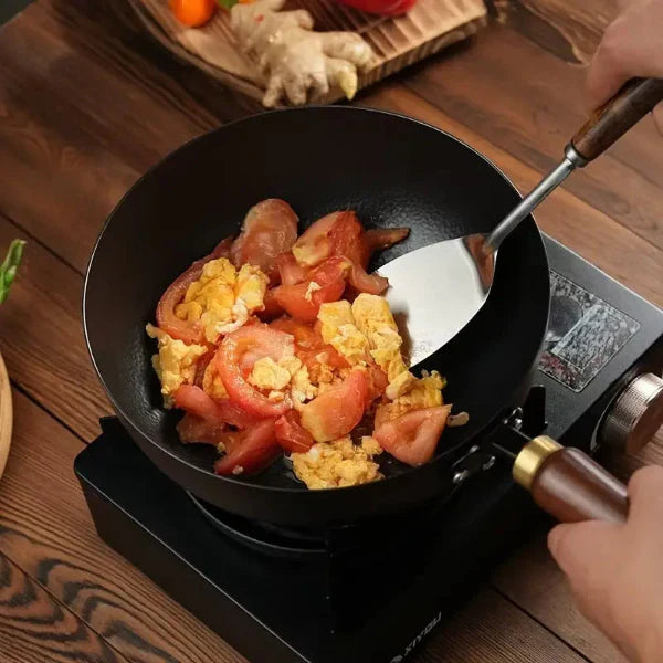 Frying pan with tomatoes and eggs on a wooden table