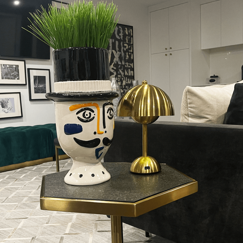 Decorative vase with face design on a small table in a living room setting.