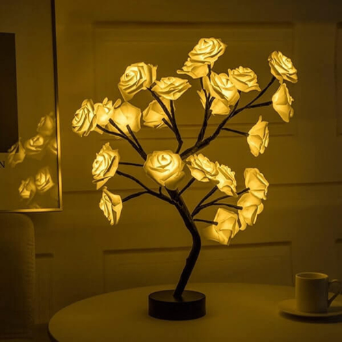 Decorative lamp shaped like a tree with illuminated roses on a table.