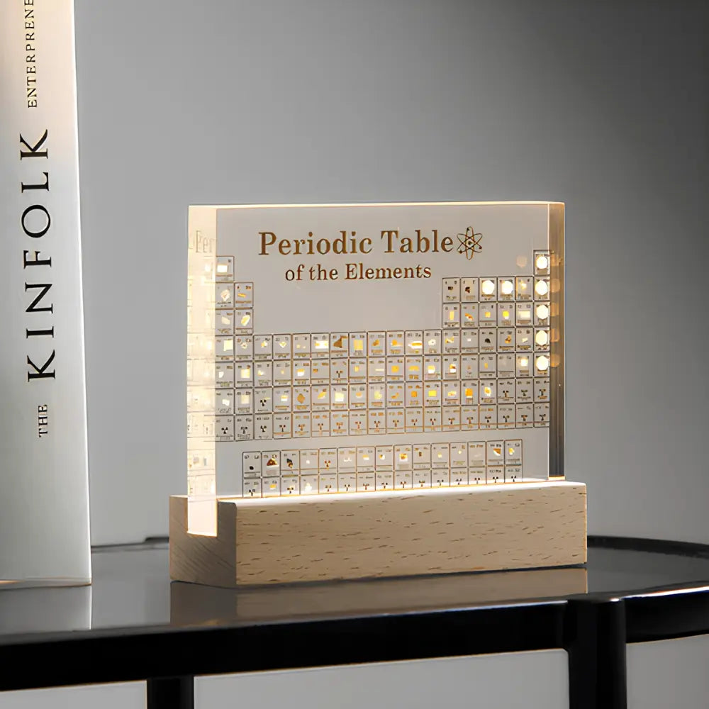 Luminous periodic table of elements on a wooden base with Kinfolk branding.