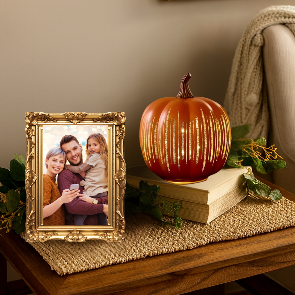 Decorative pumpkin with string lights on a book next to a gold-framed photo of a family.