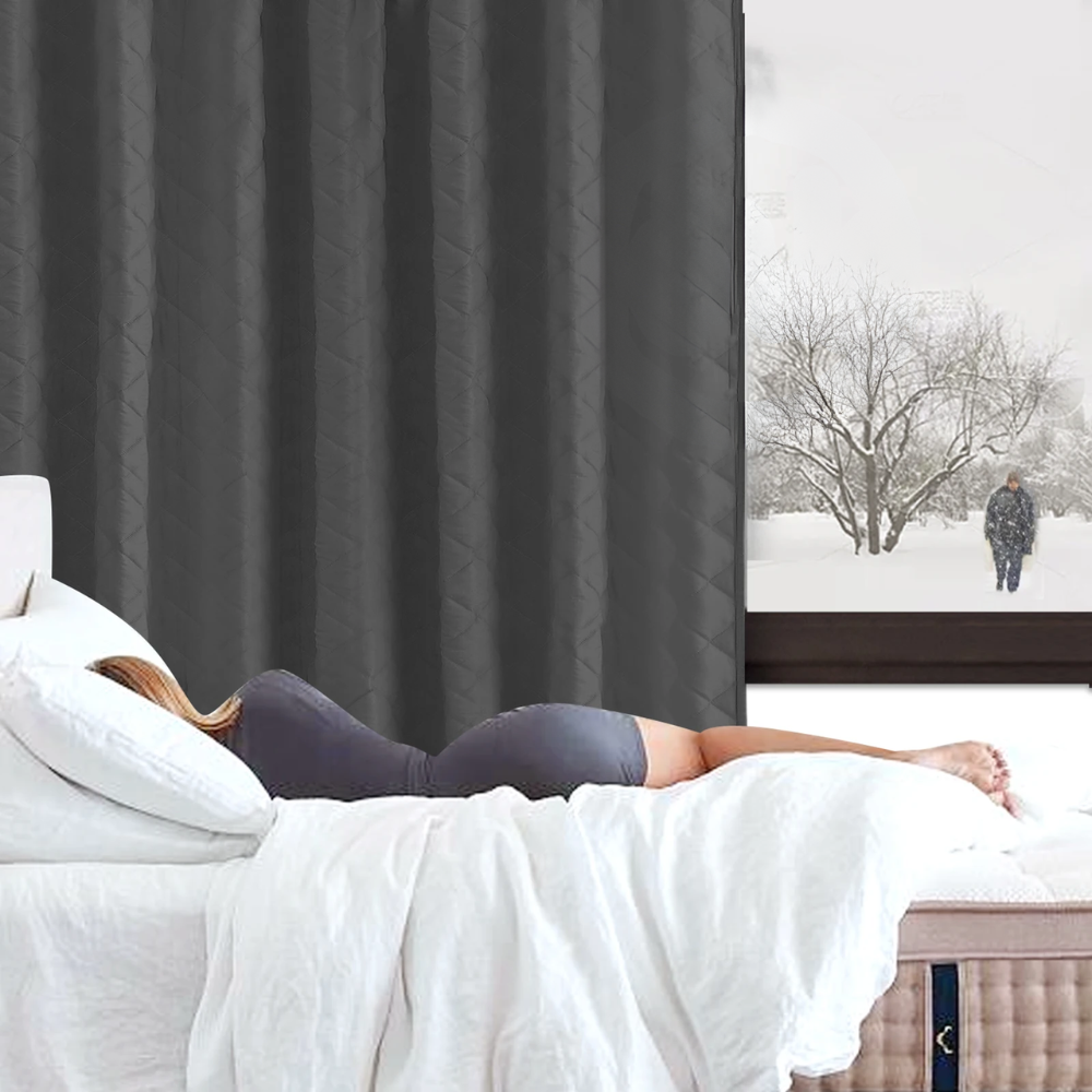 Person lying on a bed with a snowy landscape outside the window