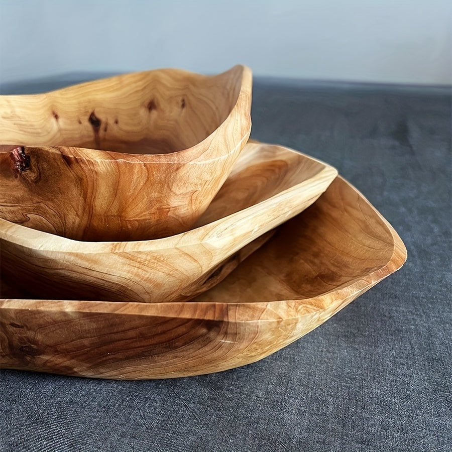 Three wooden bowls of varying sizes on a textured surface