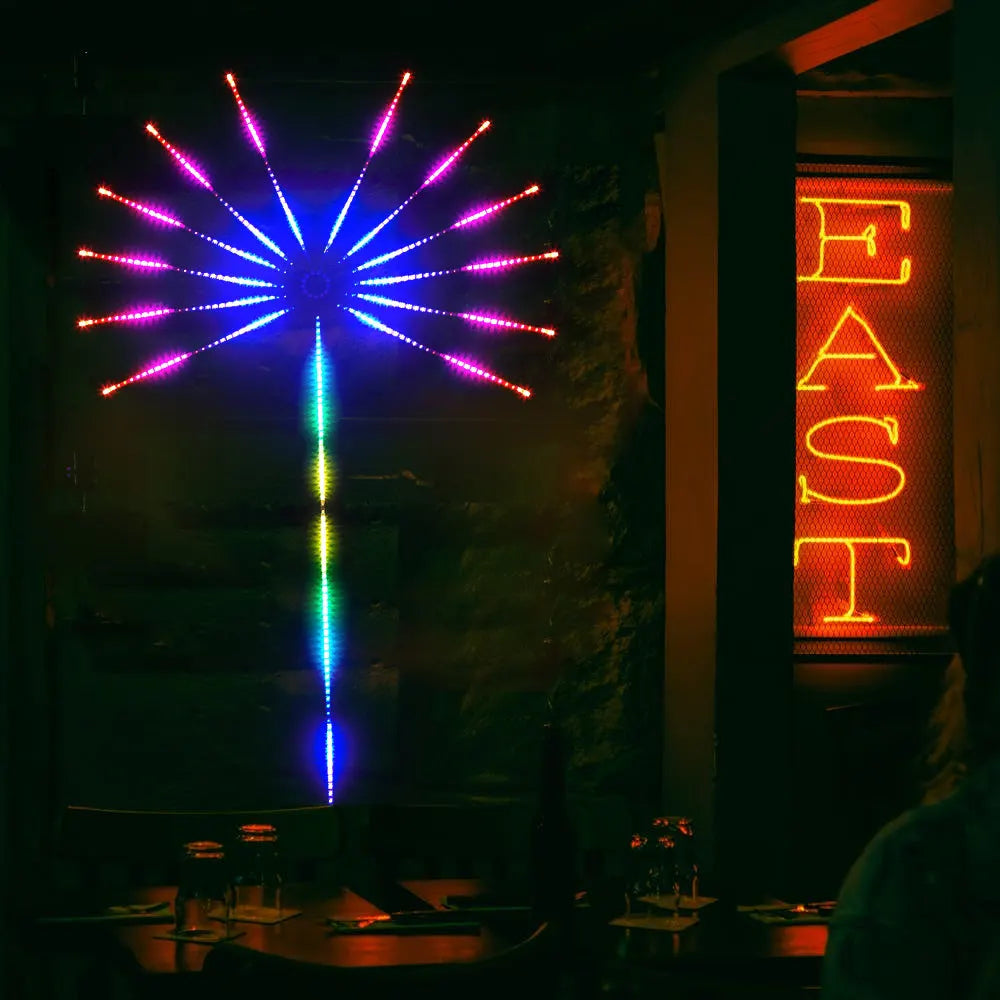 Neon light display with colorful starburst design and 'EAST' sign in a dark setting.