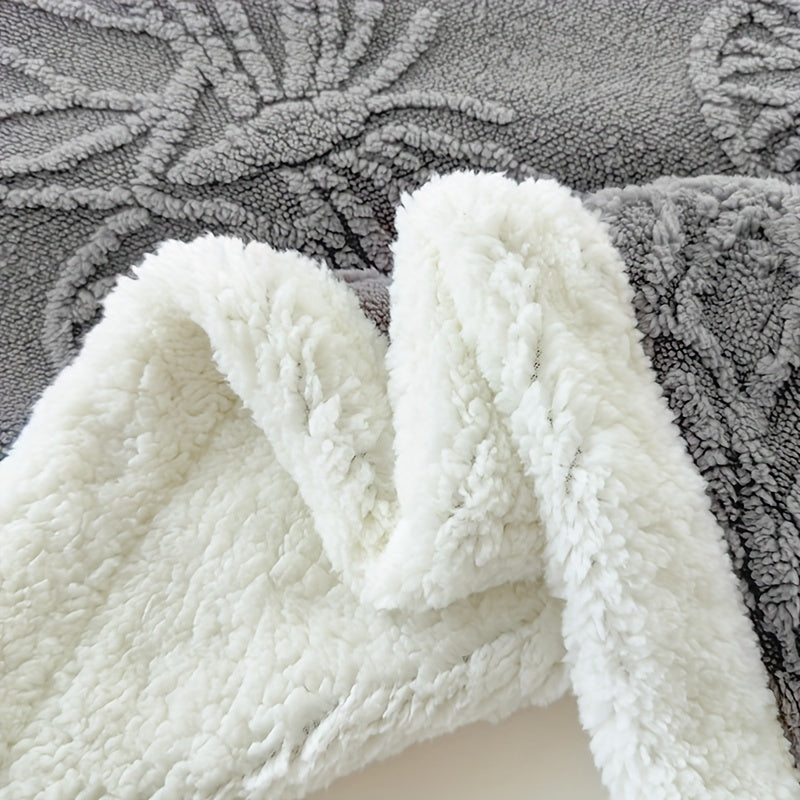Close-up of a textured gray rug with a white blanket draped over it.