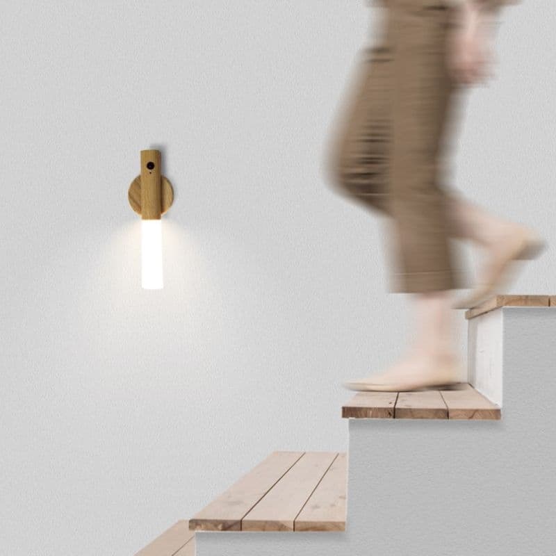 Person walking up a set of stairs with a wall-mounted light fixture on a plain background