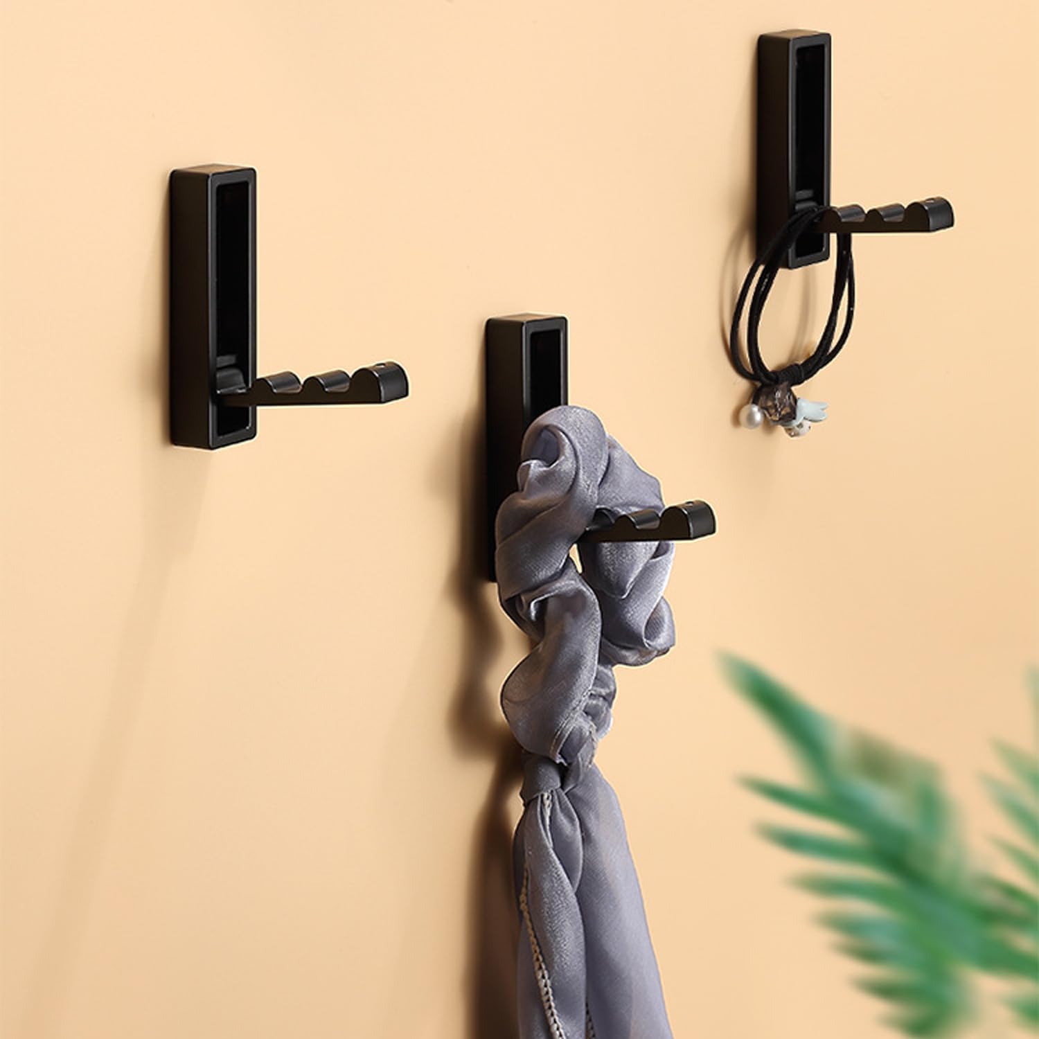 Black wall hooks with a gray scrunchie on a beige background