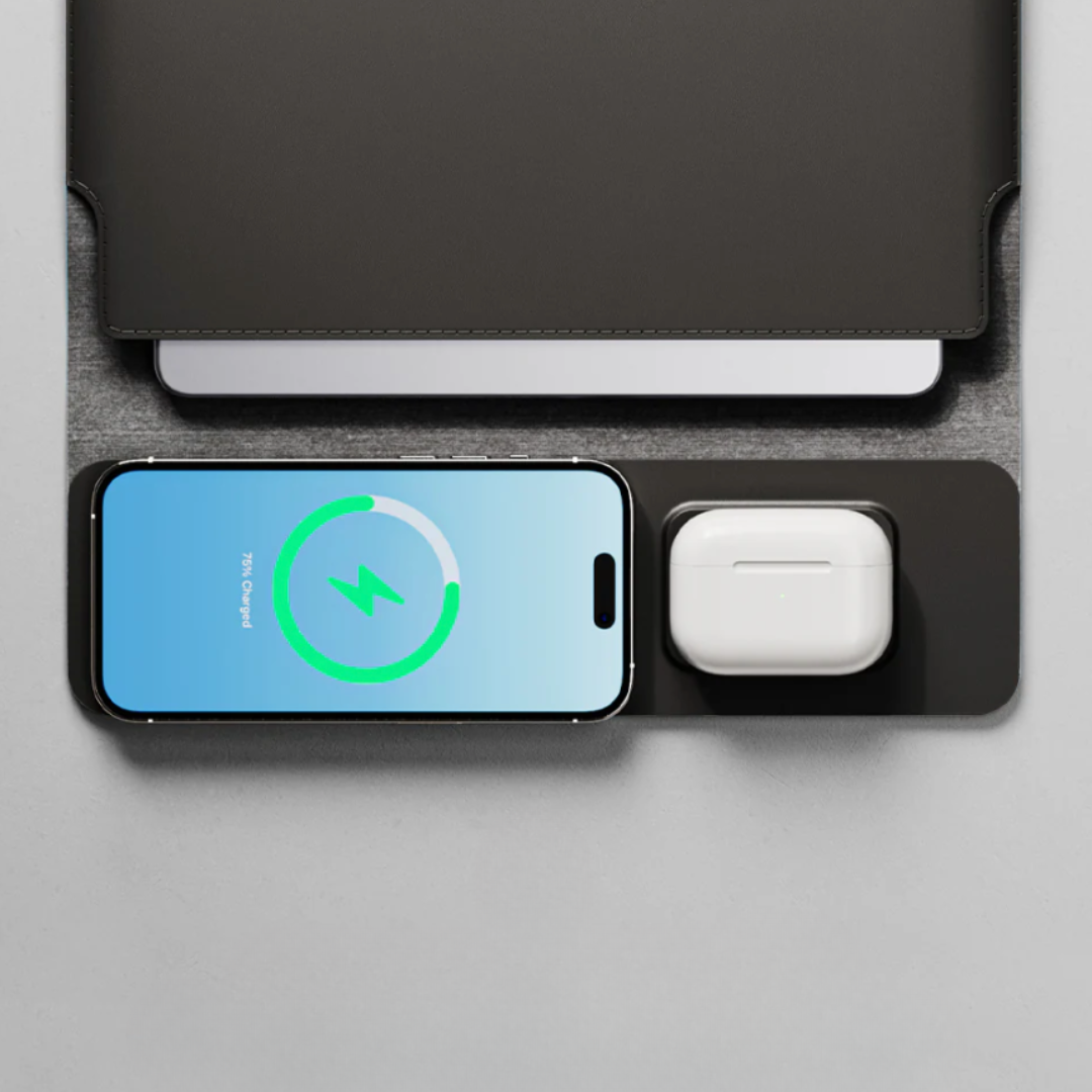 Black multi-device charging dock with smartphone, wireless earbuds, and tablet on a gray surface.
