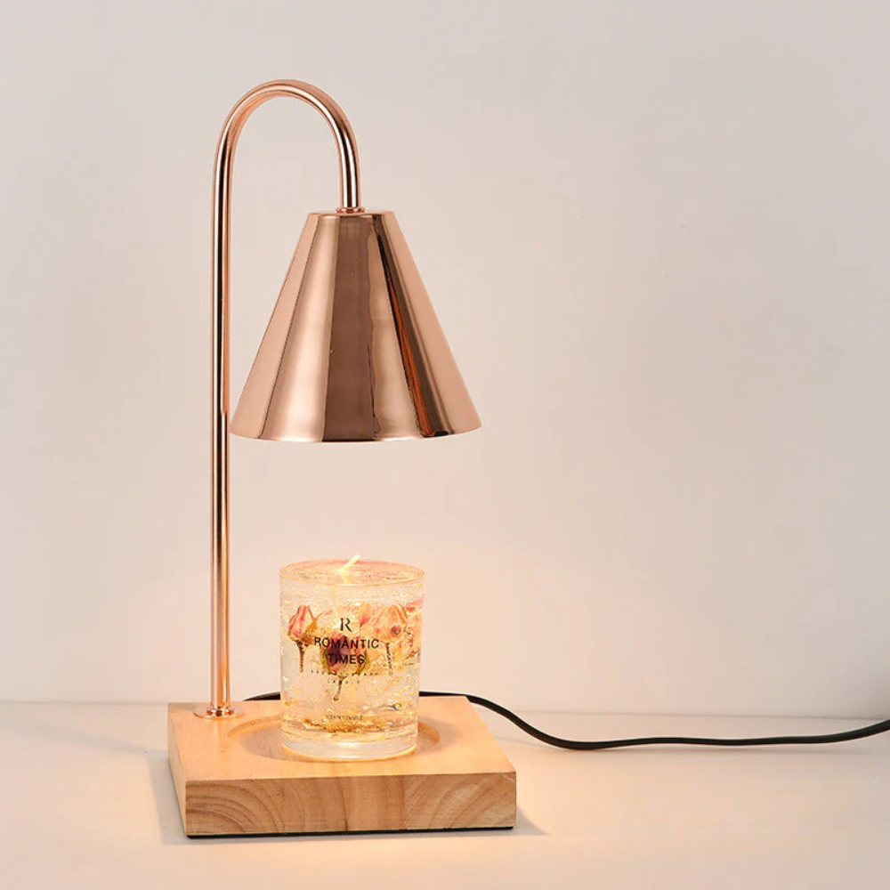 Copper table lamp with wooden base and lit candle on a neutral background