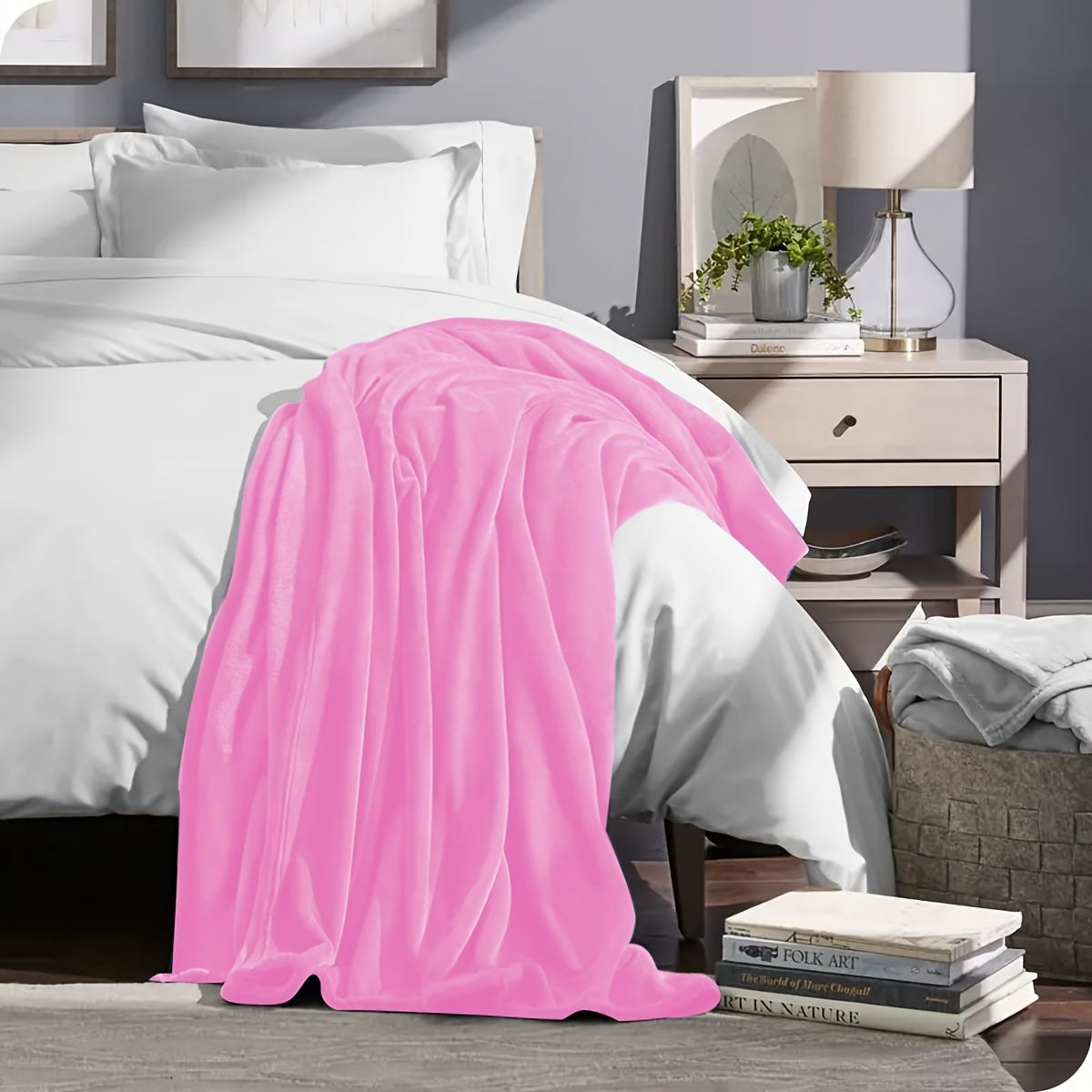 Pink blanket draped over a bed in a bedroom setting with a nightstand and lamp.