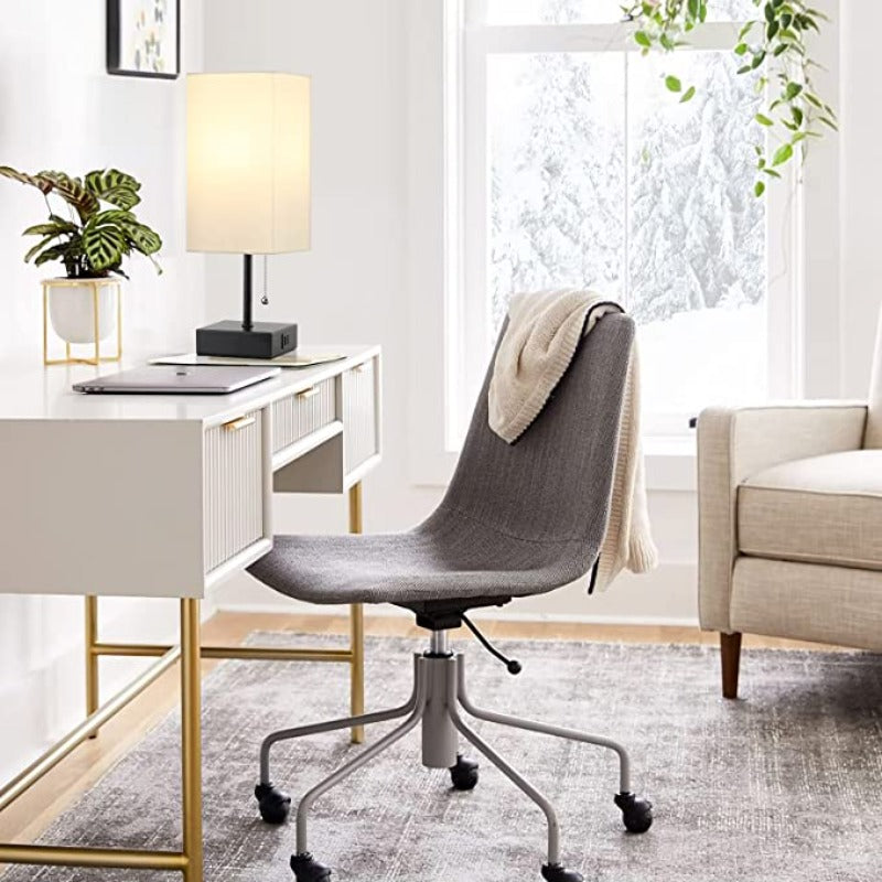 Modern home office with a desk, chair, lamp, and decor.