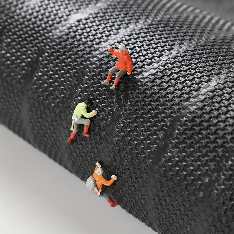 Three small figurines climbing a textured black surface
