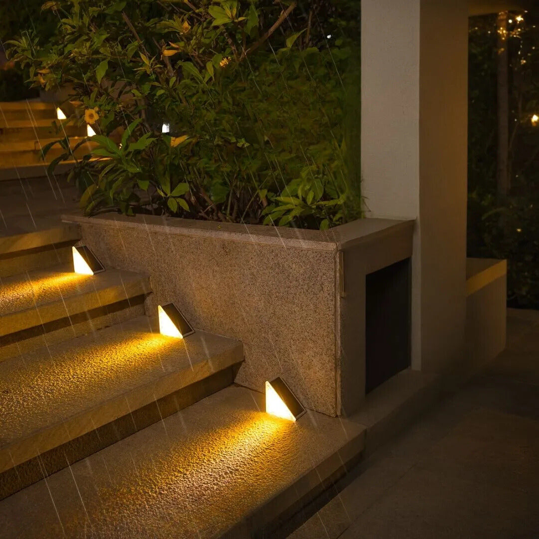 Staircase with embedded lights at night, surrounded by greenery