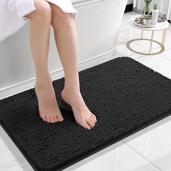 Person stepping onto a black bath mat in a bathroom setting.