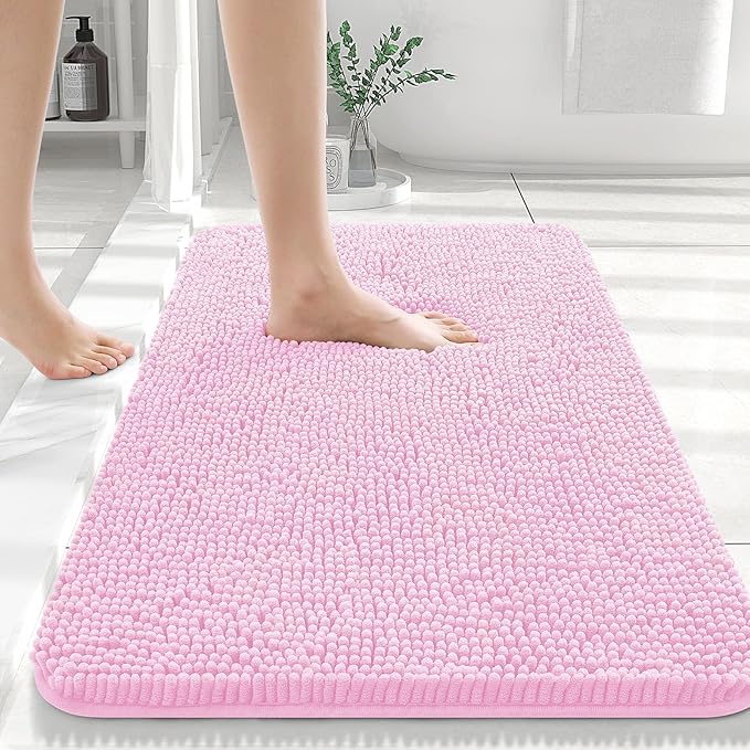 Pink bath mat on a bathroom floor with a person stepping onto it.