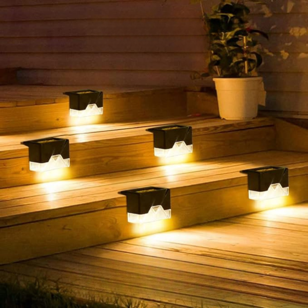 Solar-powered deck lights on wooden steps with a plant in the background.