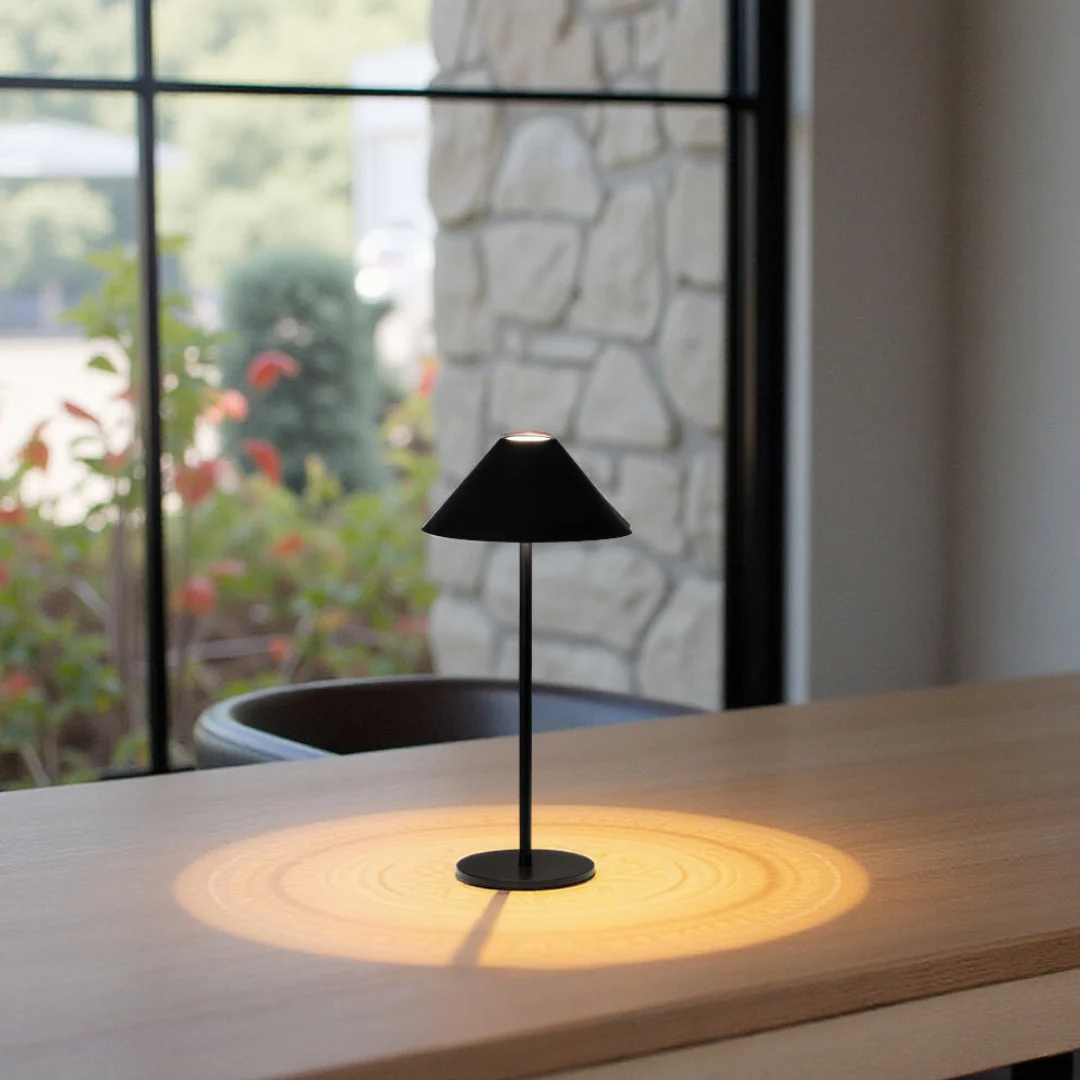 Black table lamp on a wooden surface with a blurred outdoor background