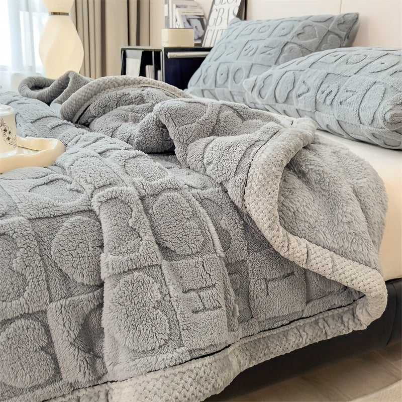 Gray textured blanket on a bed with pillows in a cozy bedroom setting.