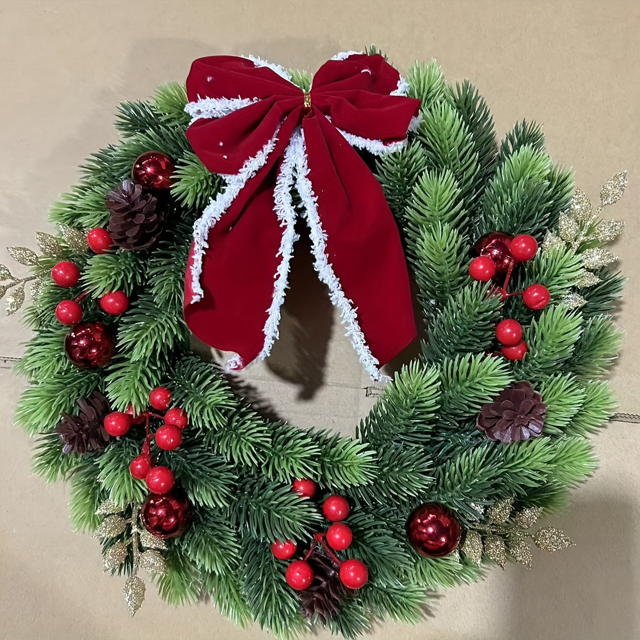 Christmas wreath with red berries and a large red bow on a beige background