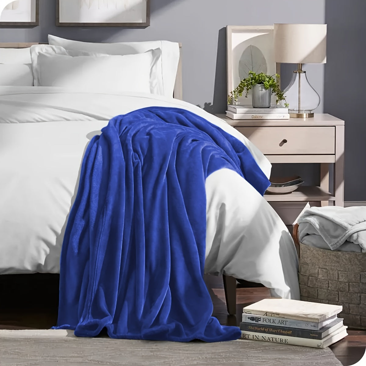 Blue blanket draped over a bed in a bedroom setting with a nightstand and lamp.