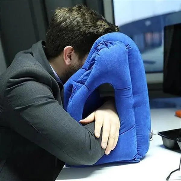Person using a blue travel pillow at a desk