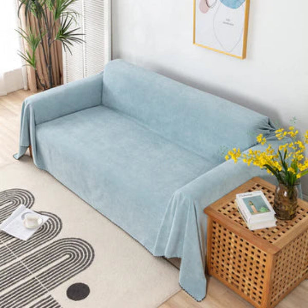 Light blue sofa cover draped over a sofa in a living room with a wooden side table and decorative items.