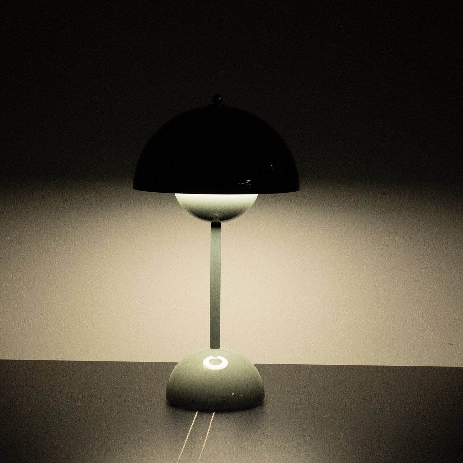 Modern table lamp with black shade on a dark surface against a dark background