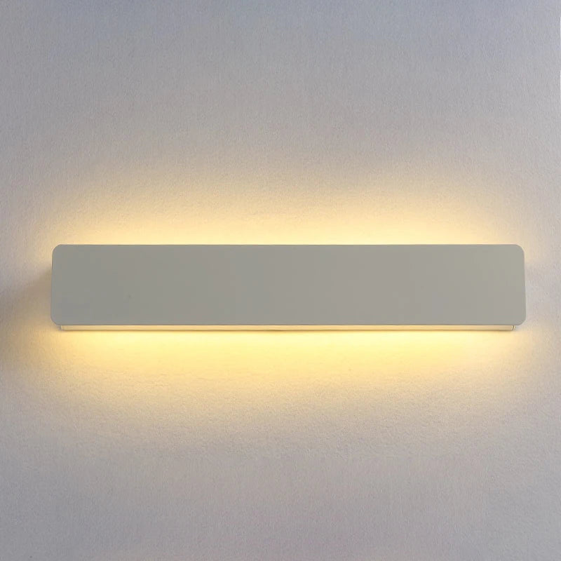 Rectangular wall light fixture on a plain wall with a soft glow.