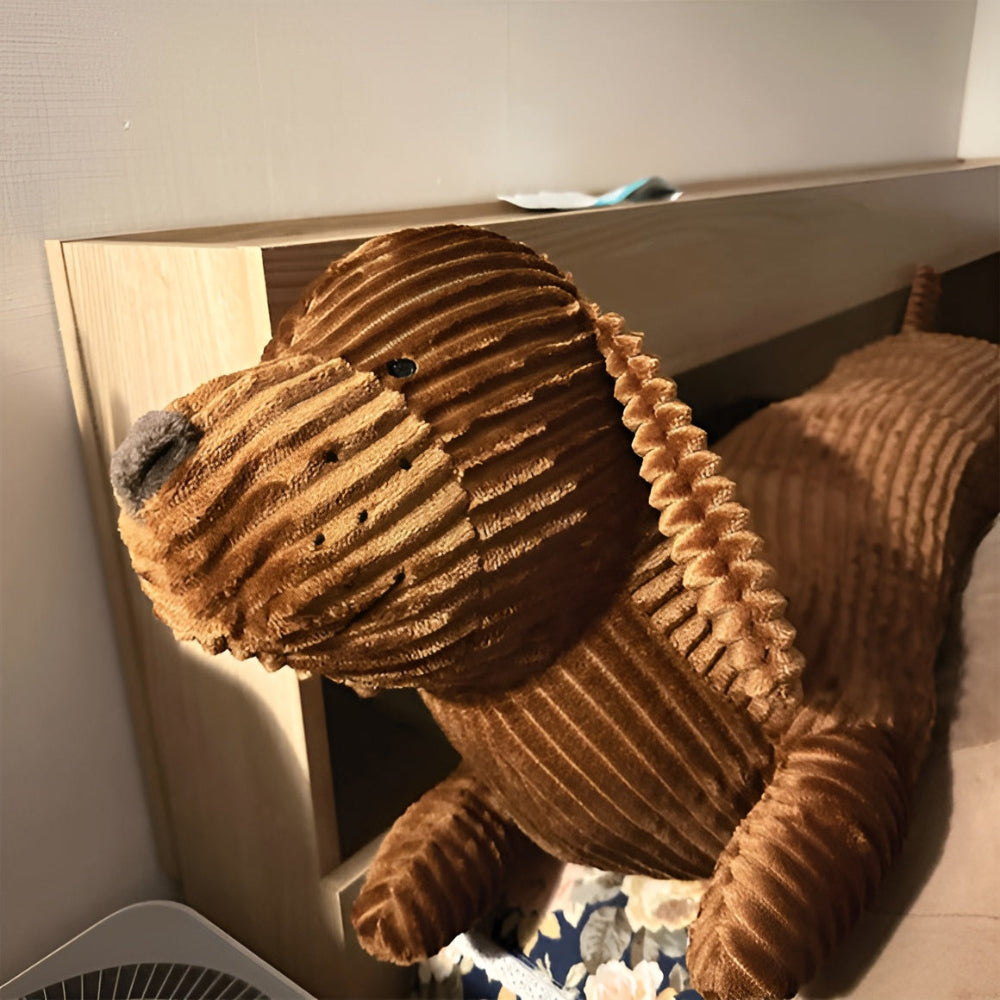 Brown plush lion toy on a wooden shelf with a neutral background