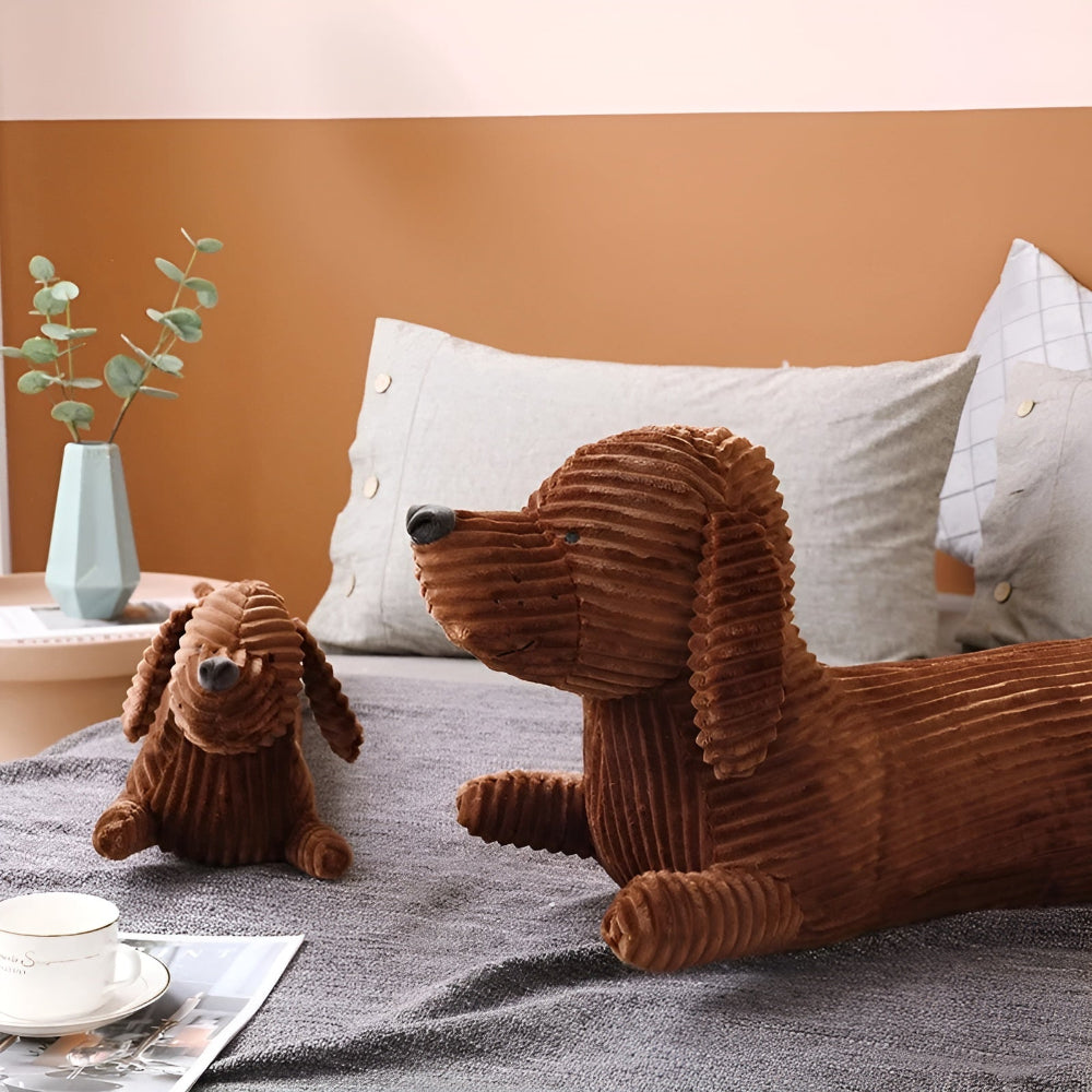 Two brown dog-shaped cushions on a bed with a neutral background
